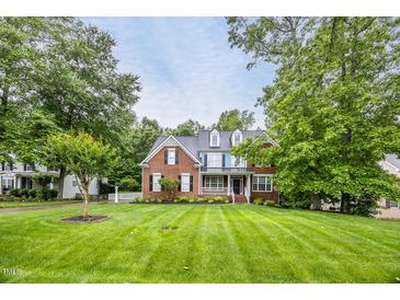 Charming brick two-story home featuring a well-manicured lawn, dormers, and a welcoming front porch at 244 Mantle Dr, Clayton, NC 27527