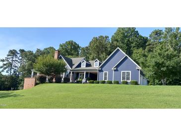 Charming blue two-story home with a well-manicured lawn and inviting front porch at 4874 Thom Rd, Mebane, NC 27302