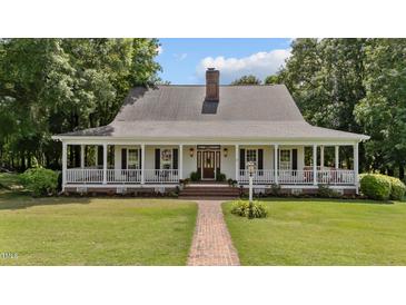 Charming home with a sprawling front porch, brick walkway, chimney, and lush landscaping at 5308 Stableview Ct, Holly Springs, NC 27540