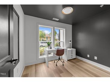 Modern home office features gray accent wall, contemporary desk, and natural light from a window with a view at 710 W North St # 103, Raleigh, NC 27603