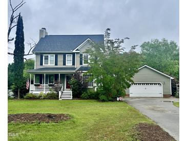 Charming two-story home with a covered porch, manicured lawn, and attached two-car garage at 7621 Troy Stone Dr, Fuquay Varina, NC 27526
