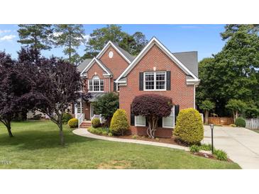 Beautiful brick home with manicured lawn, lush landscaping, and a charming walkway at 1004 Taywood Way, Apex, NC 27502
