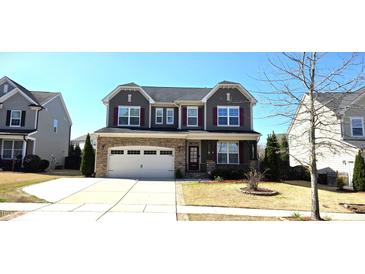 Charming two-story home features a stone accent garage and well-maintained lawn at 1116 Trotter Bluffs Dr, Holly Springs, NC 27540