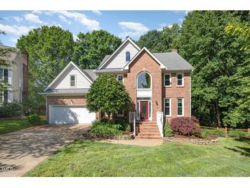 Charming two-story brick home with landscaped front yard and inviting red front door at 122 N Fern Abbey Ln, Cary, NC 27518