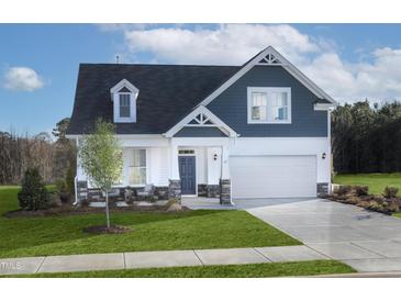 Charming two-story home with blue and white siding, a well-manicured lawn, and an attached two car garage at 135 Harmony Ranch Lane, Franklinton, NC 27525