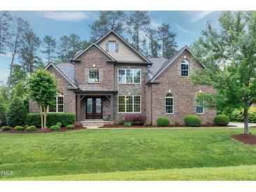 Beautiful brick home featuring manicured landscaping, a stone facade, and a covered front entrance at 1540 Sandybrook Ln, Wake Forest, NC 27587