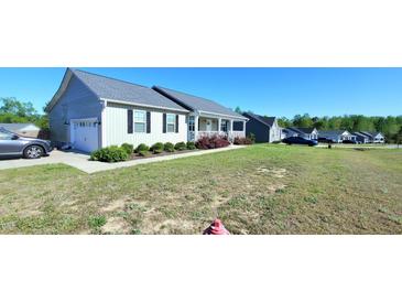 Inviting home featuring a covered porch, attached garage, and a beautifully landscaped front yard at 212 Placid Pond Dr, Broadway, NC 27505