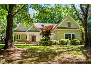 Charming home featuring a landscaped front yard, covered porch, and mature trees creating a peaceful setting at 2819 Ellis Chapel Rd, Bahama, NC 27503