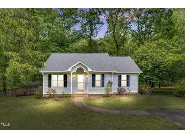 Charming single-story home featuring a well-manicured lawn, walkway, and inviting front porch, framed by lush trees at 324 Waterside Dr, Sanford, NC 27330
