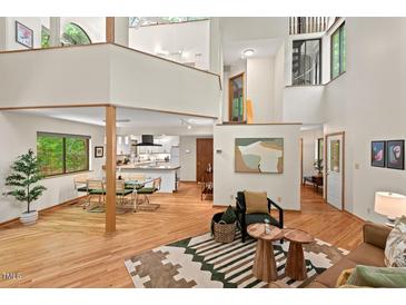 Spacious living room showcasing natural light, hardwood floors, open layout to the kitchen and unique architectural details at 6412 Heartwood Dr, Chapel Hill, NC 27516
