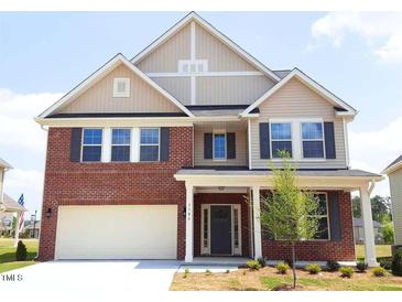 Charming two-story home with a brick and tan siding exterior, a well-manicured lawn, and an attached garage at 7584 Oakberry Dr, Raleigh, NC 27616
