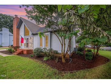 Charming home exterior features a brick chimney and nicely landscaped front yard at 100 Longneedle Ct, Raleigh, NC 27603
