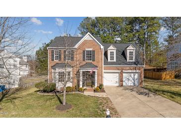 Charming brick home boasts a two-car garage, well-manicured lawn, and classic architectural details at 105 Stoney Dr, Durham, NC 27703