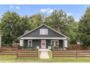 Charming home featuring a dark exterior with a pink front door and manicured front lawn at 106 E Delafield Ave, Durham, NC 27704
