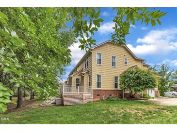 View of the rear exterior of the home featuring a deck, lush lawn, and mature trees at 11012 Southwalk Ln, Raleigh, NC 27614