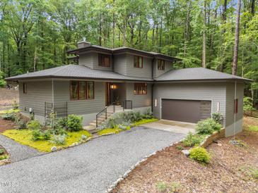 Modern home boasts meticulous landscaping and a gravel drive surrounded by a beautiful wooded area at 1115 Trailwood Dr, Raleigh, NC 27606