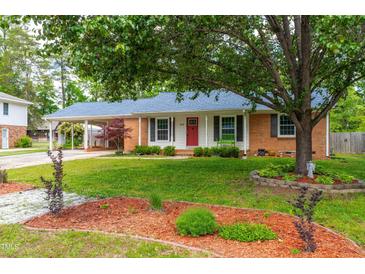 Charming single-story home with a red door, landscaped front yard, mature trees, and a covered carport at 1209 Maple Ave, Apex, NC 27502