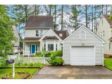Charming two-story home with a blue front door, white picket fence and a detached single-car garage at 1724 Briarforest Pl, Raleigh, NC 27615
