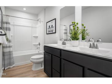 Modern bathroom featuring double vanity, framed mirror, tub, and shower combination at 314 N Coral Bells Way, Four Oaks, NC 27524