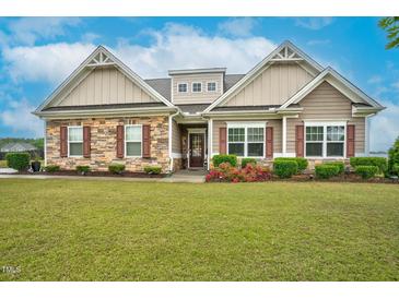Charming home with a stone and wood exterior, landscaped lawn, and beautifully manicured shrubs and flower beds at 3909 Mendenhall Dr, Zebulon, NC 27597