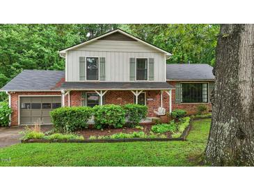 Charming two-story home featuring a brick exterior, green shutters, mature landscaping, and inviting front porch with swing at 1503 Laughridge Dr, Cary, NC 27511