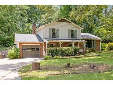 Charming two-story home with brick accents, lush landscaping, and an inviting front porch swing at 1503 Laughridge Dr, Cary, NC 27511