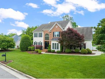 Charming two-story home featuring a brick and siding exterior, lush lawn, and mature landscaping at 2000 Katesbridge Ln, Raleigh, NC 27614