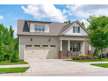 Charming home featuring a two-car garage, front porch with chairs, and beautiful landscaping at 2036 Amy Grace Ct, Fuquay Varina, NC 27526