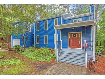 Unique blue home exterior with beautiful landscaping, a porch swing, and a welcoming front entrance at 2525 Buxton Ct, Chapel Hill, NC 27514