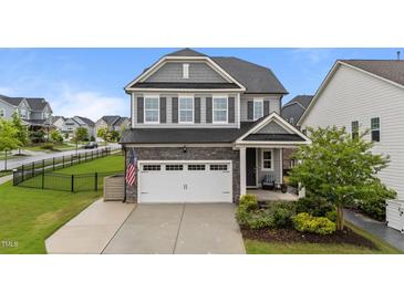 Charming two-story home featuring a gray exterior, a two-car garage, and manicured landscaping, with an American flag at 348 Golf Vista Trl, Holly Springs, NC 27540