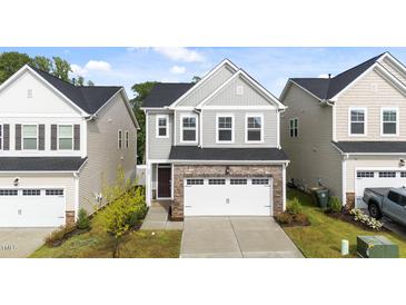 Charming two-story home featuring stone accents, a two-car garage, and manicured landscaping at 380 Garden Vine Trl, Raleigh, NC 27610