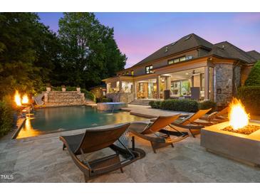 A luxury backyard features an in-ground pool, jacuzzi, sun loungers, and a fire pit, perfect for relaxing at night at 3829 Westbury Lake Dr, Raleigh, NC 27603