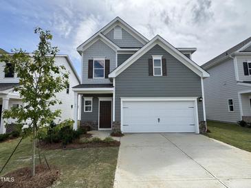 Charming two-story home with a two-car garage, manicured lawn, and professionally designed landscaping at 51 Commons Cir, Clayton, NC 27520