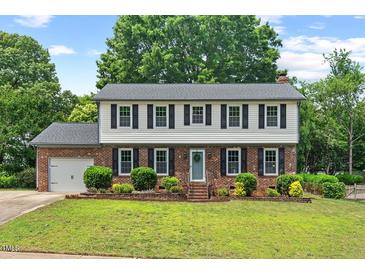 Charming two-story brick home with black shutters, a manicured lawn, and beautiful landscaping at 5409 Knollwood Rd Rd, Raleigh, NC 27609