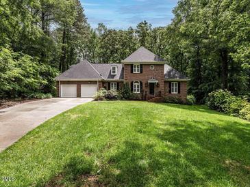 Beautiful brick home with manicured lawn, attached two-car garage, and mature trees at 104 Deer Park Ln, Cary, NC 27518