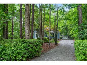 Charming home featuring a long gravel driveway surrounded by lush greenery and tall trees at 10816 Bent Branch Dr, Raleigh, NC 27603