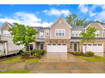 A charming townhome with stone accents, a two-car garage, lush landscaping, and a neatly paved driveway on a sunny day at 1156 Craigmeade Dr, Morrisville, NC 27560