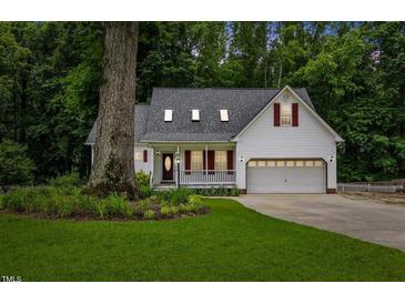 Charming white house featuring a well-maintained lawn, a two-car garage, and a cozy front porch at 119 Valleycastle Ct, Clayton, NC 27520