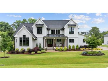 Beautiful two story home with manicured lawn, dark window trim, and covered porch at 1229 Perry Bluff Dr, Wake Forest, NC 27587