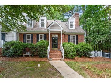 Charming brick home featuring dormer windows, black shutters, and a neatly landscaped front yard at 1703 Berwickshire Cir, Raleigh, NC 27615
