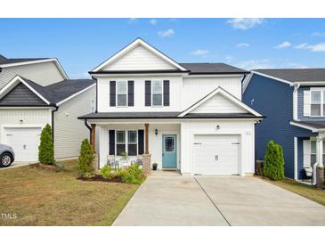Charming two-story home features a light blue front door, garage, and manicured lawn at 21 Diploma Dr, Clayton, NC 27520