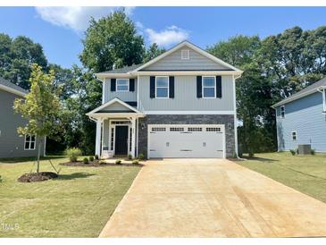 Charming two-story home featuring a two-car garage, stone accents, and a well-manicured lawn, perfect for suburban living at 315 New Twin Branch Ct, Smithfield, NC 27577
