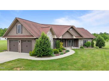 Charming home featuring a two-car garage, stone accents, and a beautifully landscaped front yard with lush green grass at 3465 Covington Trl, Mebane, NC 27302