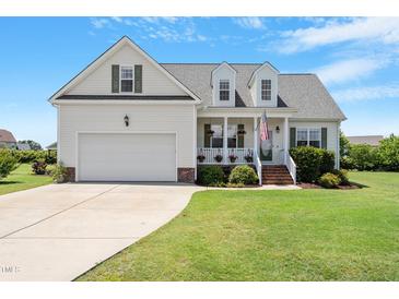 Charming home featuring a manicured lawn, a welcoming front porch, and an attached two-car garage at 518 Spruce Meadows Ln, Willow Springs, NC 27592