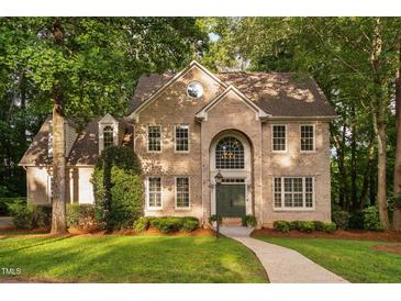 Charming brick home featuring a symmetrical facade, arched entryway and lush green lawn at 7808 Umstead Forest Dr, Raleigh, NC 27612