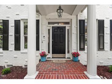 Charming home featuring a black front door, white brick, shutters, brick walkway, and potted plants at 1404 Kings Lassiter Way, Raleigh, NC 27614