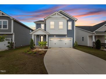 Charming two-story home featuring blue siding, white trim, a two-car garage, and manicured landscaping at 159 Wood Orchid Ln, Garner, NC 27529