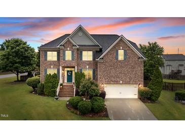 Charming brick home featuring a well-manicured lawn and inviting front entrance with blue door and shutters at 19 Arch Oak Ct, Clayton, NC 27527