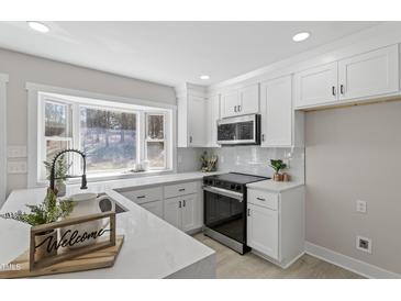 Bright kitchen features white cabinets, quartz countertops, stainless steel appliances, and a large bay window at 4307 Pope Rd, Durham, NC 27707