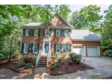 Charming two-story brick home with manicured landscaping, shutters, and a two-car garage at 104 Tutbury Pl, Cary, NC 27519